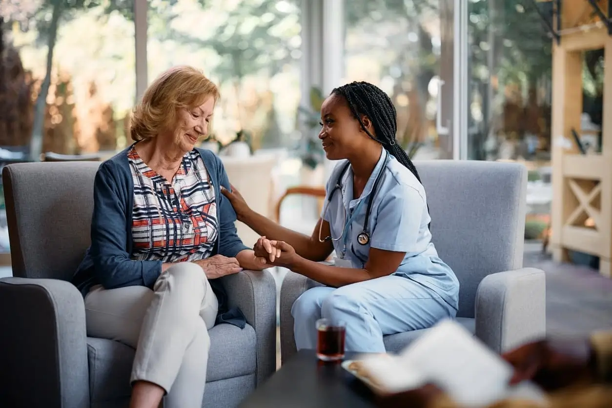 Caring black nurse consulting senior woman while talking to her in nursing home.